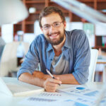 Handsome businessman in casual working in office on background of his partners